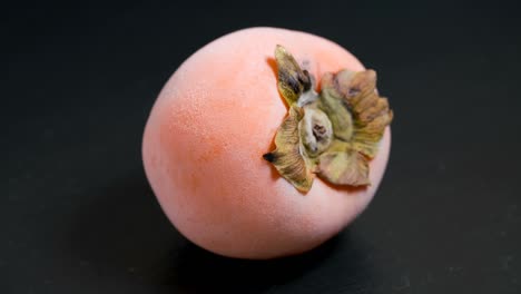 defrosting yellow persimmon on a black background