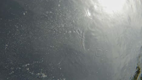 rock thrown and submerge in deep clear water on sunny day. close up