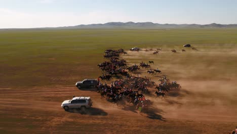 cinematic drone shot of a group of jockeys riding in a fast canter and gallop over the mongolian steppe