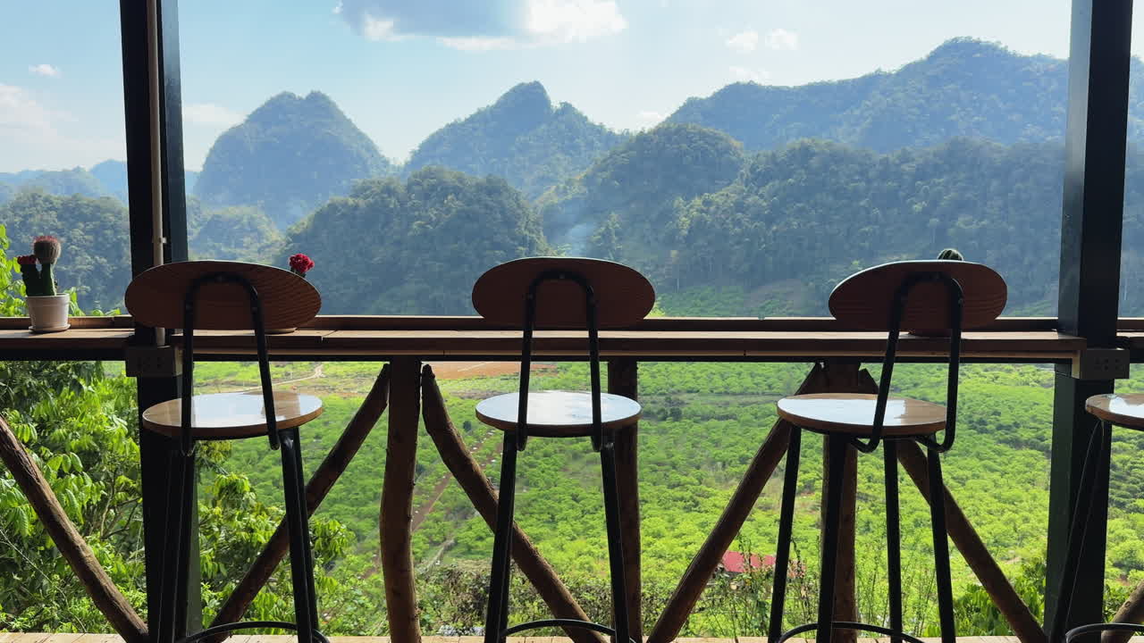 Plum Blossom Valley, Vietnam. Scenic cafe viewpoint with chairs overlooking a stunning mountain range and lush valley. Perfect for relaxation and enjoying nature's beauty.