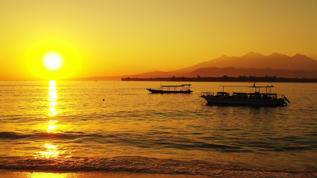Beautiful yellow sunset reflecting off the surface of the rippling water at a beach island resort