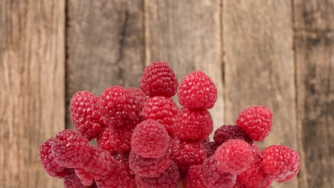 Raspberry berries on a wooden background. Side view. Loop motion. Rotation 360.