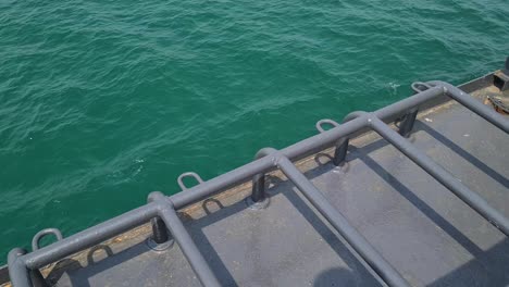 ferryboat side deck while cruising in turquoise sea water, close up detail
