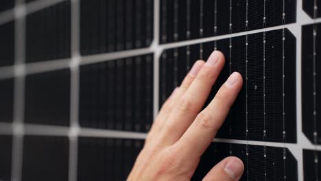 primer plano de la mano tocando la superficie del panel solar comprobando la eficiencia