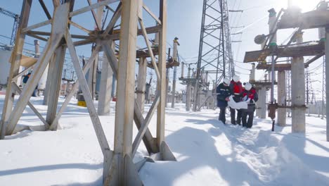 engineers reviewing plans at a snowy power plant