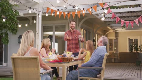 young man taking to family members while having lunch outdoors