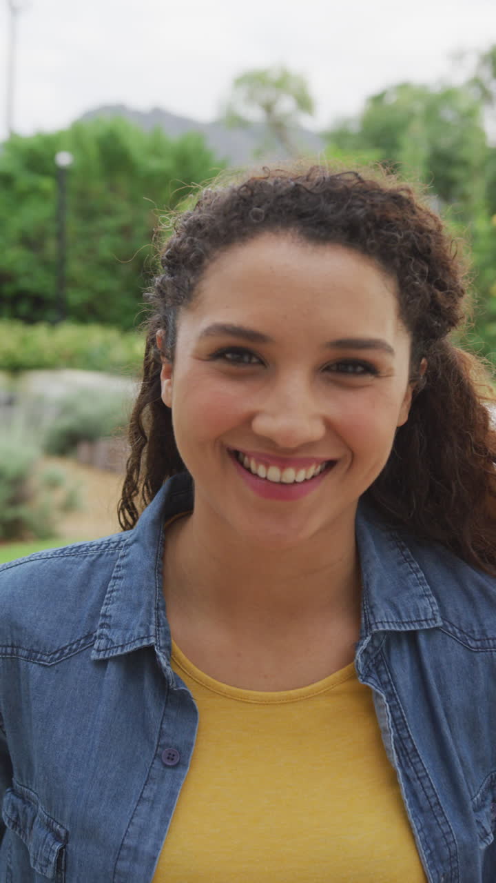 video vertical de una mujer biracial feliz sonriendo a la cámara