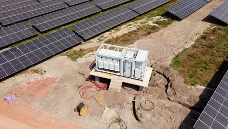 aerial orbit view of mv inverter station and cabling reel at a solar field