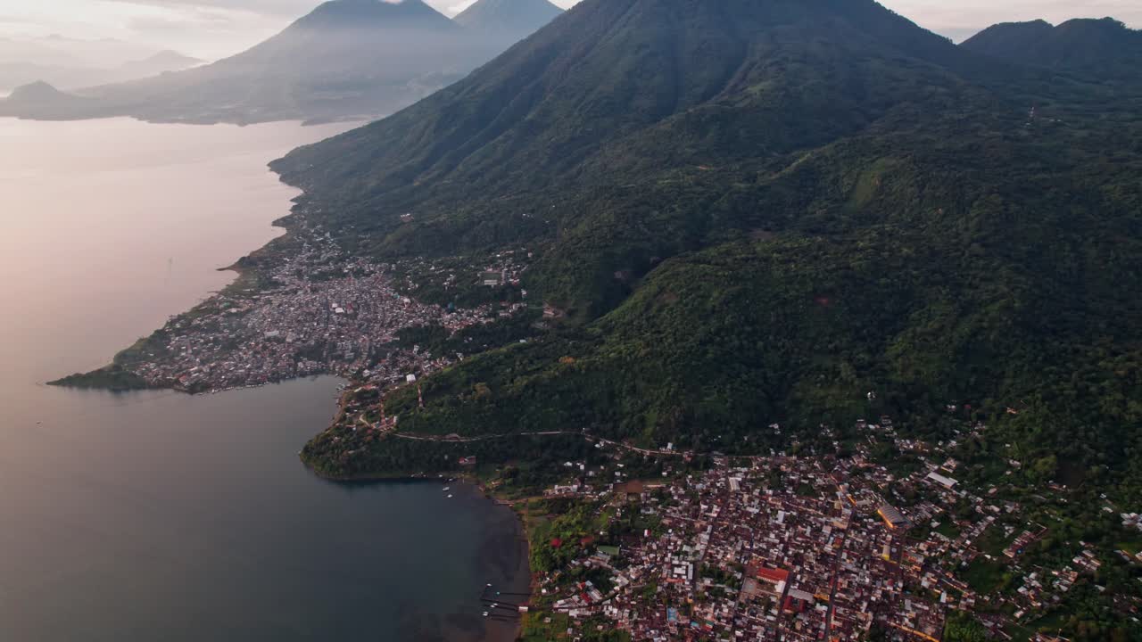 A breathtaking high-altitude drone shot captures the tranquil village of San Pedro La Laguna nestled on the shores of Lake Atitlán at sunrise