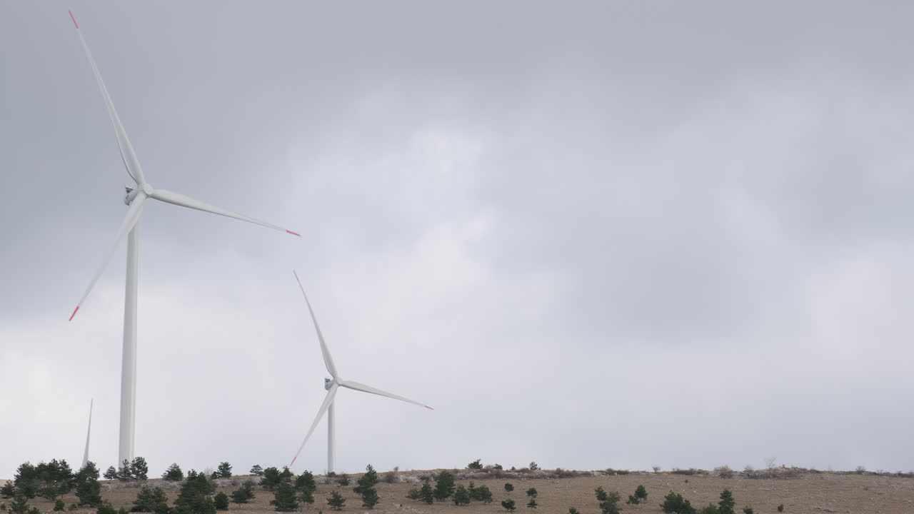 A large wind turbine plant. Sustainable and renewable green energy from the wind. Turbines arranged on a mountain plateau. Windy weather before the storm.