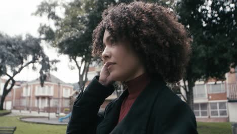 una mujer en traje con cabello rizado camina mirando alrededor en la ciudad de bogota