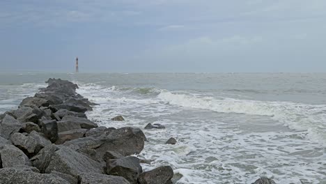 Small-waves-hitting-the-breakwater-with-Morris-lighthouse-in-the-background-during-a-foggy-afternoon