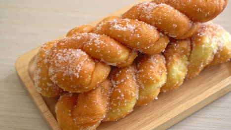 sugar doughnut in spiral shape on wooden plate