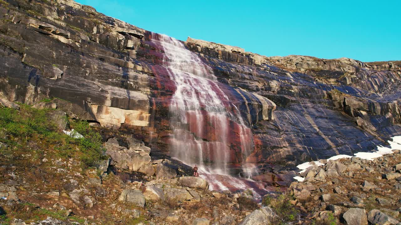 vista aérea de la cascada que cae en cascada por la roca de color rojo en el parque nacional de hardangervidda