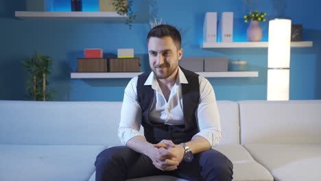 Charismatic-and-attractive-businessman-sitting-on-sofa-at-home-smiling-at-camera-and-looking-around.