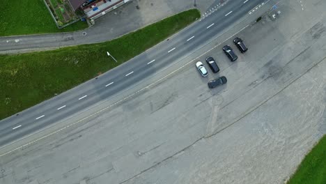 vista aérea de un coche saliendo de una zona de estacionamiento, a lo largo de una carretera en una ciudad adormecida