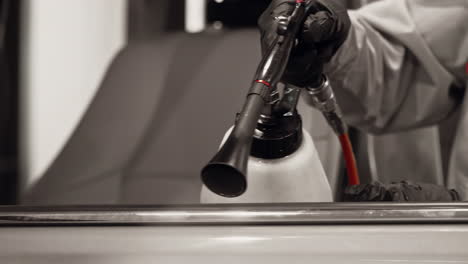 skilled engineer, wearing a black glove, meticulously cleans the car window ceiling strip using a powerful tornado gun, ensuring a spotless finish