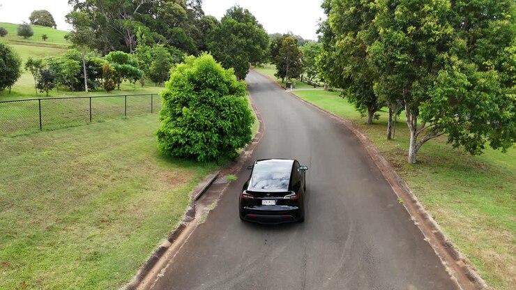 tesla-auto fährt auf einer landschaftlich reizvollen vorstadtstraße