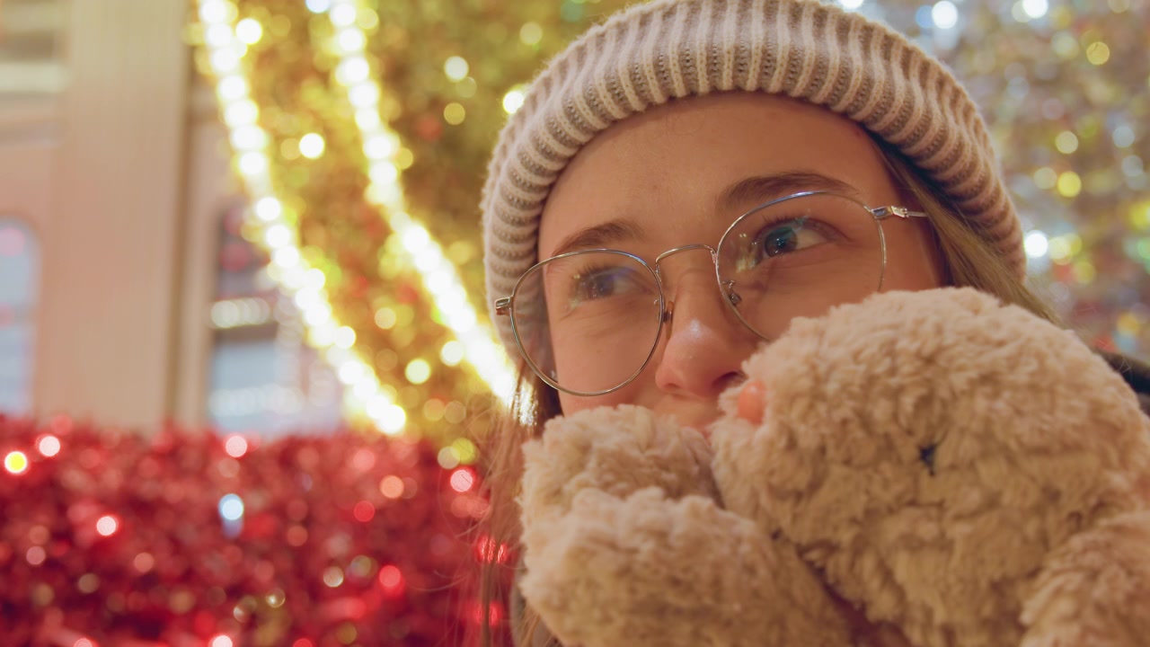 White woman pressing bunny to face amid holiday lights, emotional closeup conveying comfort and healing, soft tears and gentle smile framed by sparkling red decorations and warm seasonal glow