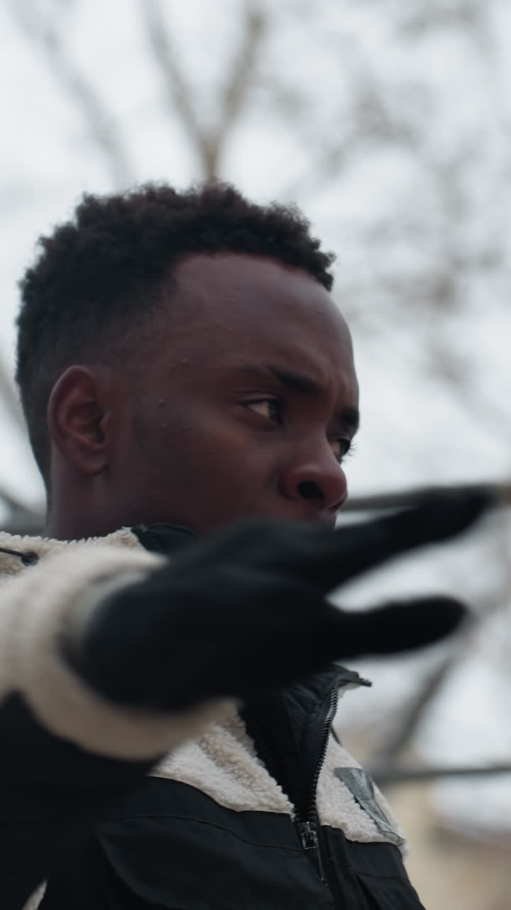 primer plano de un joven que trabaja al aire libre durante el invierno, realizando ejercicios de fitness frente a equipos de entrenamiento de madera, mientras se empuja a través del ambiente frío
