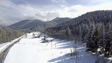 Verschneite-Landstraße,-Die-Zu-Bergen-Im-Wald-Führt