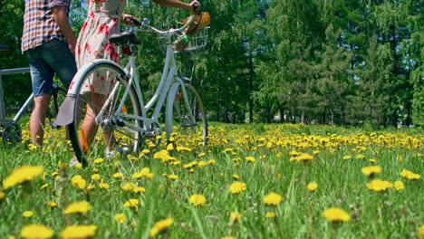 Woman-And-Man-Wear-Confortable-Clothes,-They-Carry-A-Bicycle-Walking-In-The-Meadow