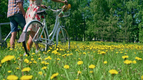 Frau-Und-Mann-Tragen-Bequeme-Kleidung,-Sie-Tragen-Ein-Fahrrad,-Das-Auf-Der-Wiese-Spazieren-Geht