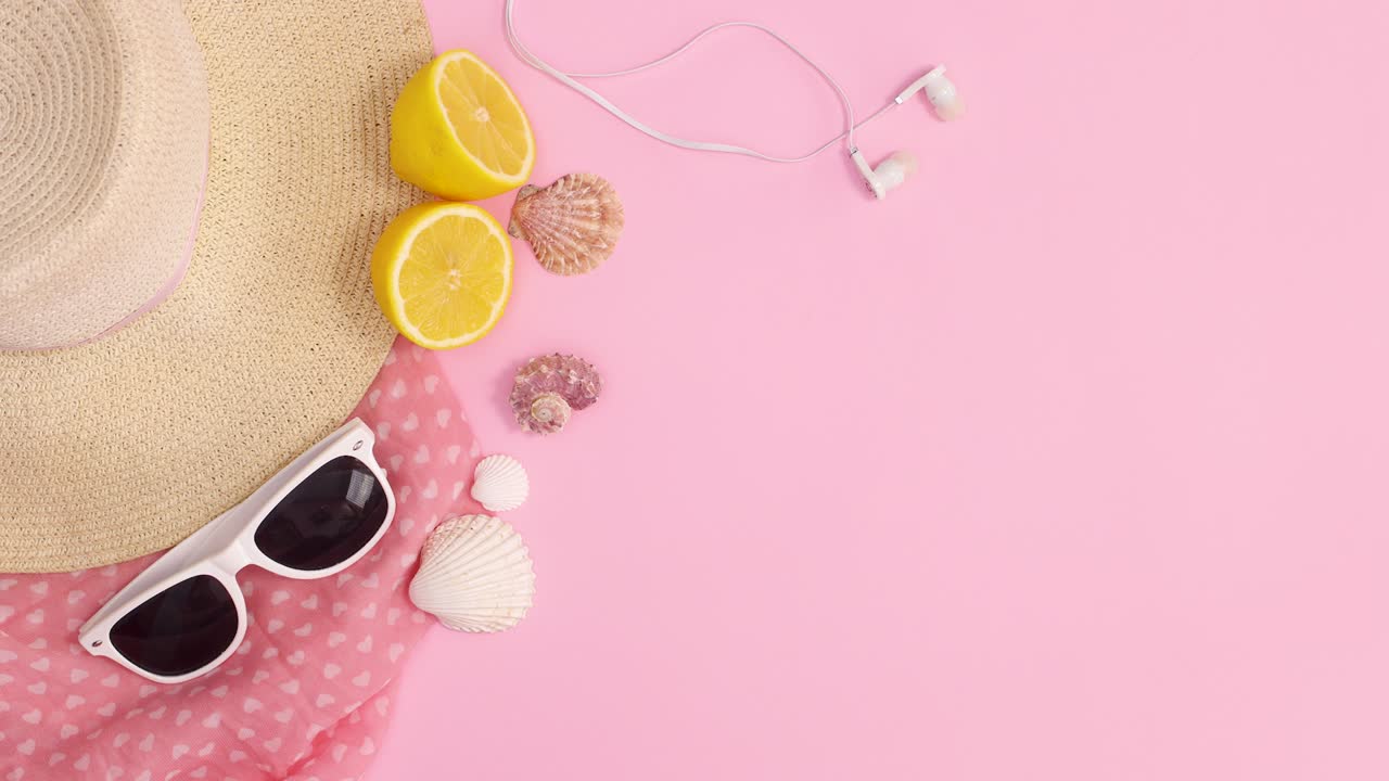 Summer trendy beach accessories with copy space frame on pastel pink background. Stop motion flat lay