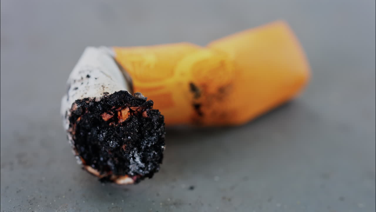 Close up of a smashed cigarette butt on a grey surface