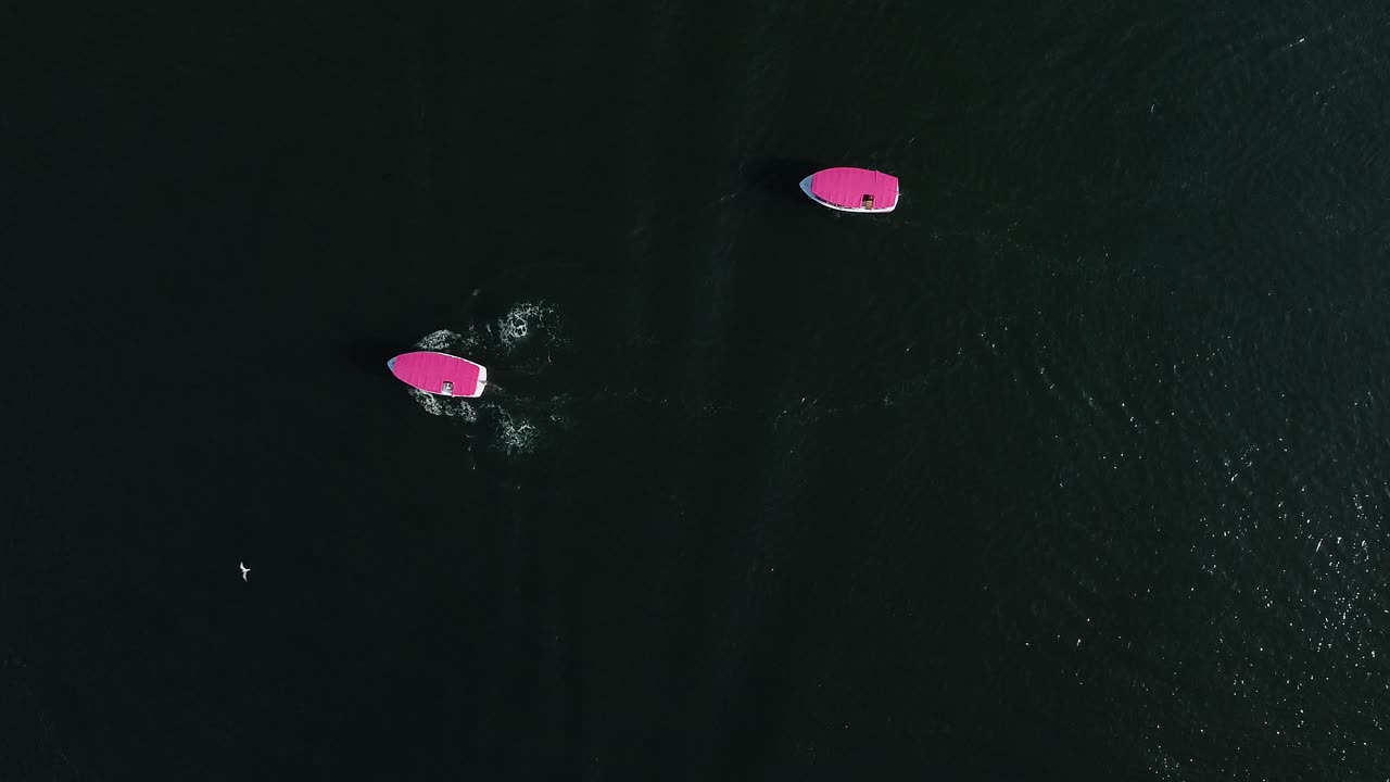vista aérea de dos barcos de fiesta rosados golpeando las estelas del barco