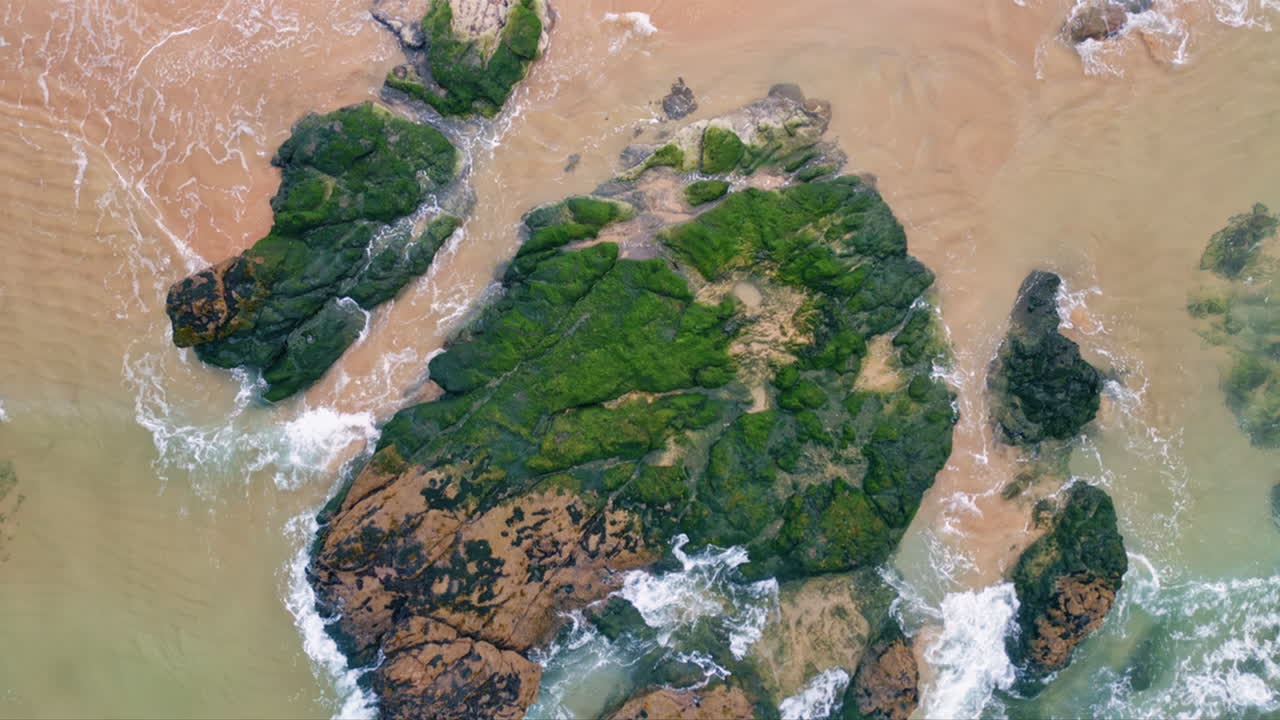 Ondas fortes do mar lavando pedras da costa em vista vertical. Oceano espumoso quebrando nas colinas.