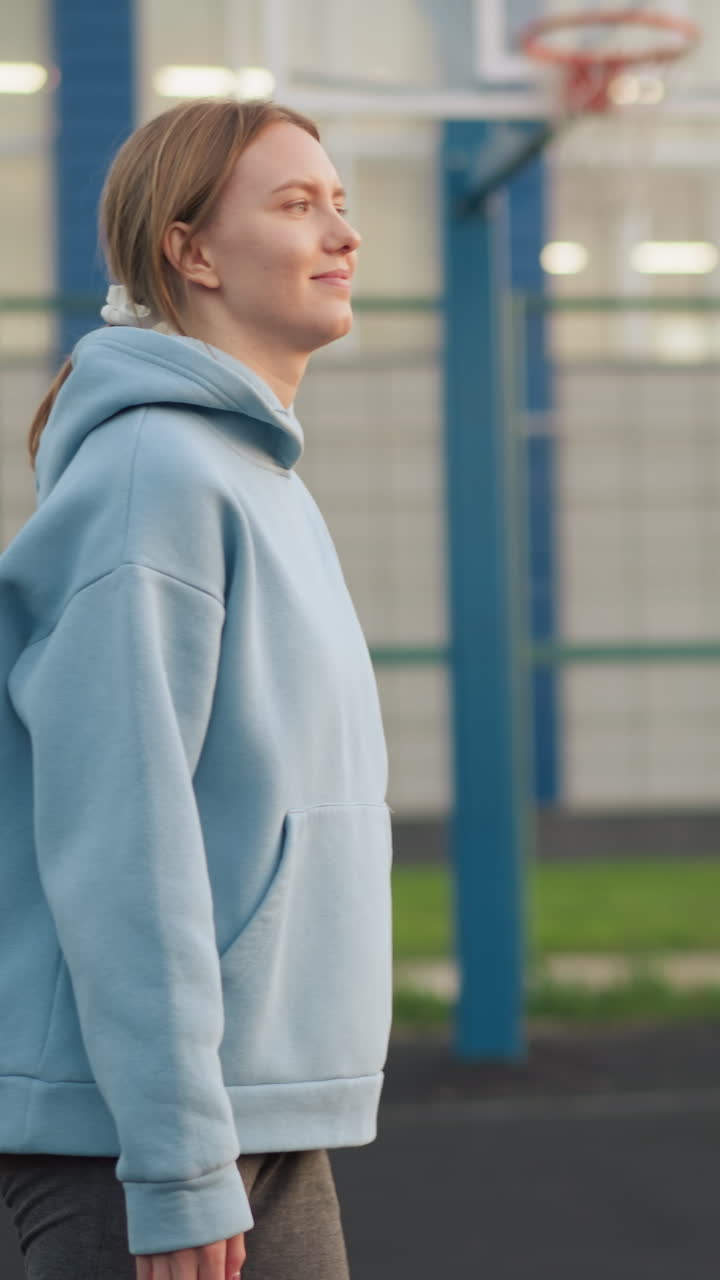 Donna con felpa con cappuccio blu serve a pallavolo, osservandola mentre lascia la sua mano, sessione di allenamento di pallavolo all'aperto con attenzione all'azione di servizio e alla tecnica atletica