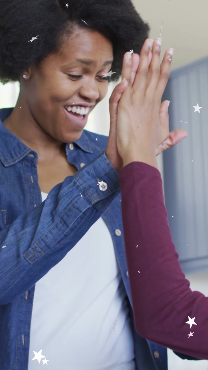 Vertical video: Teen reaching high-fiving mom in kitchen with pen, white stars drifting celebrating