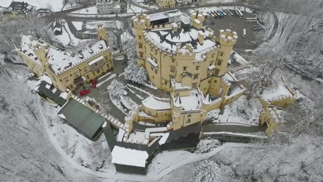 aerial view of hohenschwangau flying to top of the castle in winter