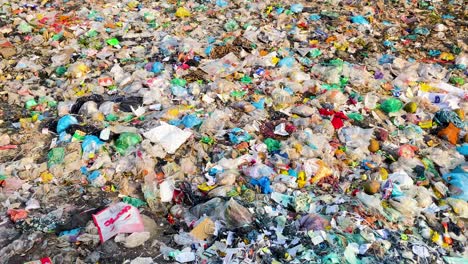 Ein-Haufen-Plastikmüll-Und-Plastiktüten-Auf-Einer-Mülldeponie,-Ökologie,-Umweltverschmutzung,-Schwenkaufnahme-Eines-Menschlichen-Fußabdrucks