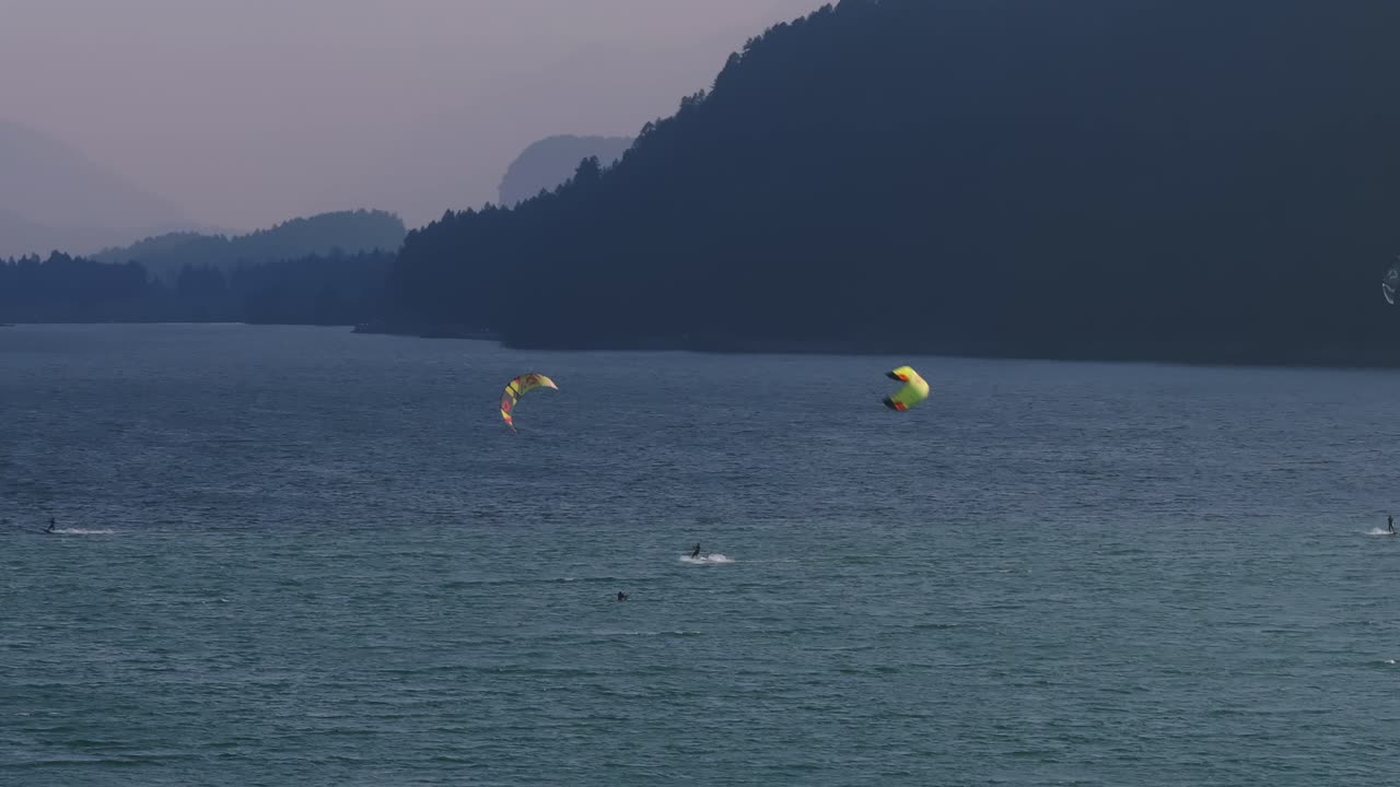 Peaceful lake view with paragliders flying above the water and scenic mountains