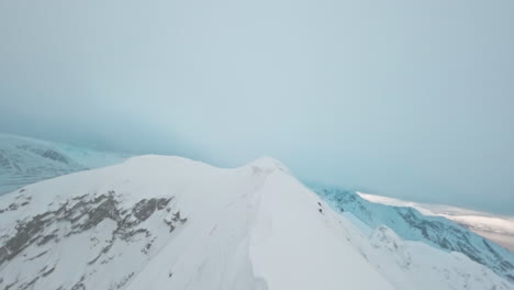snow-covered mountain ridge with fjord view under misty sky, tromsø, norway