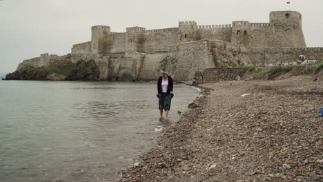 a woman hardly trying to walk on the pebbles on the rocky seaside