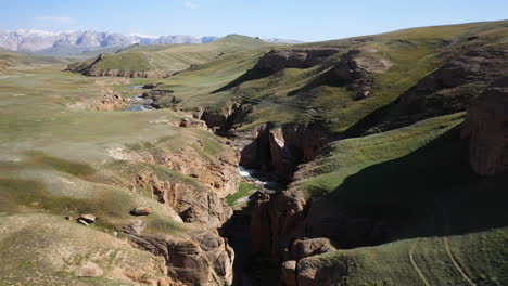 Epic-revealing-drone-shot-going-over-the-crevasse-near-a-small-river-near-the-Kel-Suu-lake-in-Kyrgyzstan