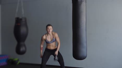 woman working out with dumbbells and punching bag in gym