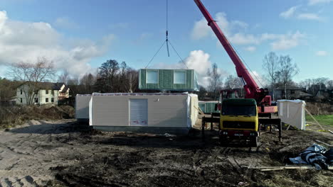 assembly of modular prefab house with mobile crane in daytime