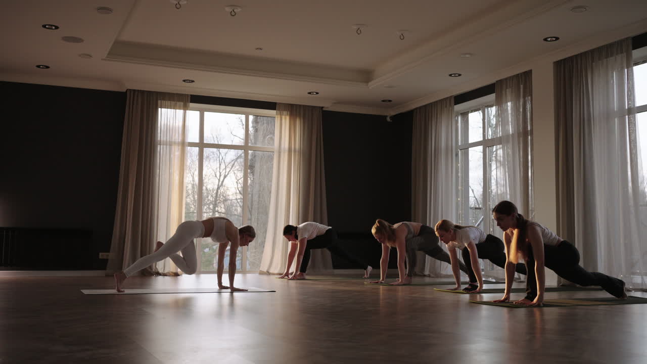 Young Caucasian sporty people practicing yoga lesson with instructor. Caucasian group of women exercising healthy lifestyle in fitness studio. Sport activity gymnastics class. Slow motion.