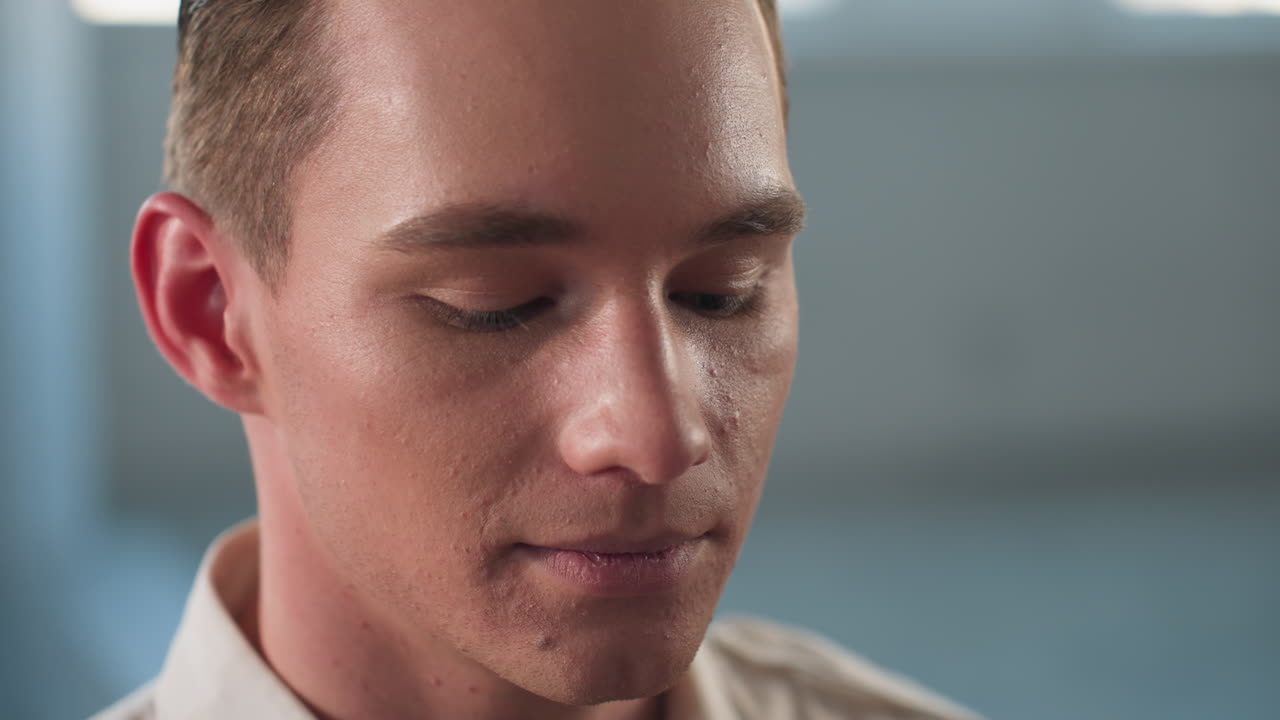 hand of makeup artist applying liquid foundation on man face as he opens eyes wide capturing precise cosmetic application technique with slight blurred background