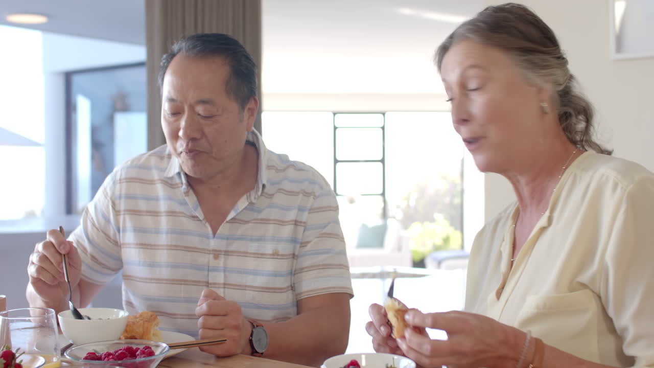Eating breakfast together, senior couple enjoying vacation meal at home