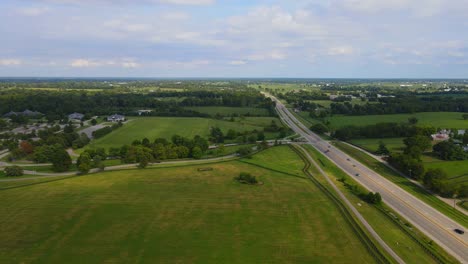 highway cutting through rolling farmland and green fields in the kentucky countryside, usa