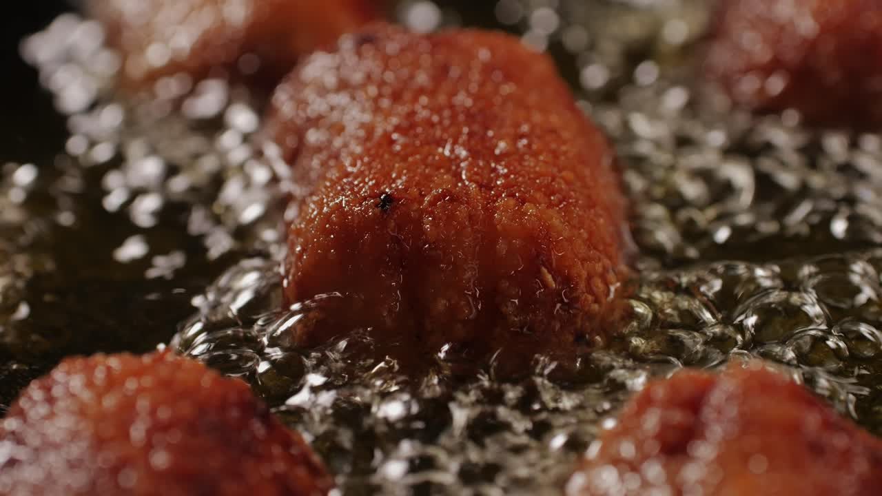 Portuguese croquettes broiling on black frying pan close-up macro. Breaded croquette of fish, potatoes and ham. Man cooking spanish food. High quality 4k footage
