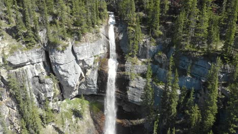 Luftbild,-Das-Sich-Wegbewegt,-Malerischer-Blick-Auf-Den-Wasserfall-An-Der-Seite-Des-Berges,-Umgeben-Von-Pinien