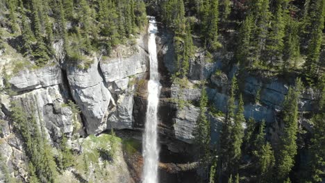 vista aérea que se aleja, vista panorámica de la cascada en la ladera de la montaña rodeada de pinos