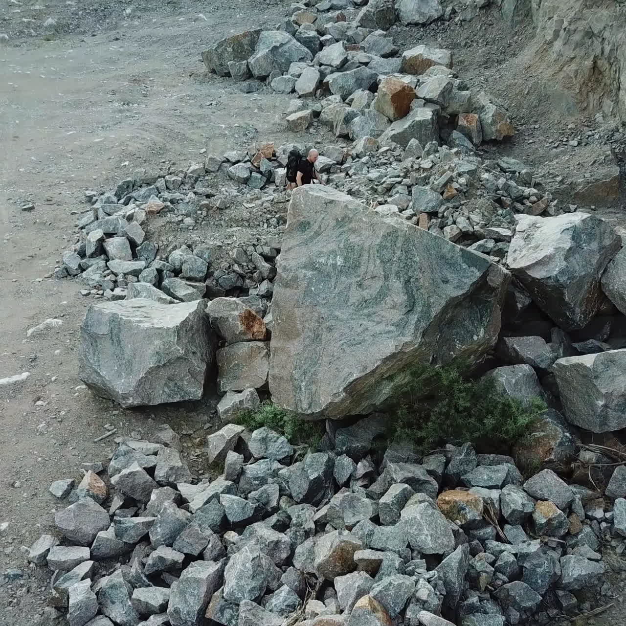 Hiker man going through the stone trail and comes into a rocky place. Aerial view of a tourist trekking in the mountains outdoors.