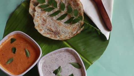 rotating oothappam - dosa - south indian breakfast using rice lentil and vegetables served with coconut chutneyisolated on green background